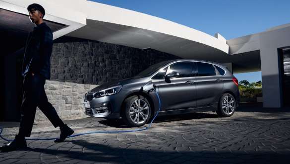 BMW 225xe Active Tourer F45 hybride rechargeable, vue de trois quarts de profil devant un bâtiment BMW 225xe Active Tourer F45 hybride rechargeable, vue de trois quarts de profil devant un bâtiment avec modèle
