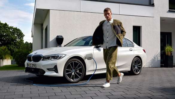 BMW Série 3 Berline hybride rechargeable 2021 G20, vue de trois quarts avant branchée à une borne de recharge BMW Série 3 Berline hybride rechargeable 2021 G20, vue de trois quarts avant branchée à une borne de recharge avec modèle