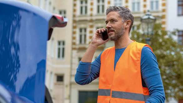 Homme se tient devant le coffre de la BMW
Homme se tient devant le coffre de la BMW avec un téléphone portable et un triangle de signalisation dans les mains