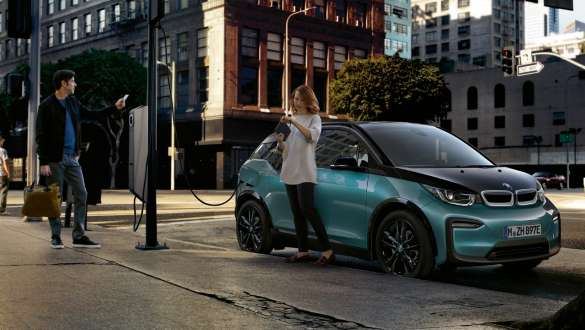 BMW i3 I01 2018 à une borne publique de recharge rapide Un couple recharge sa BMW i3 sur une borne de recharge publique I01 2018 Blue Ridge Mountain avec accent Frozen Grey metallic