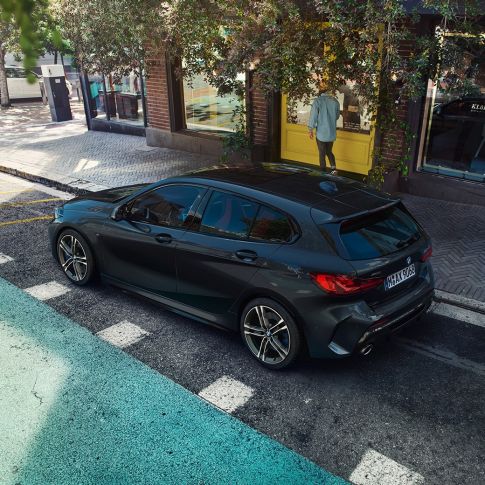 BMW M135i xDrive, en stationnement F40. BMW M135i xDrive en Saphirschwarz metallic, vue de trois quarts de profil en plongée, en stationnement F40.