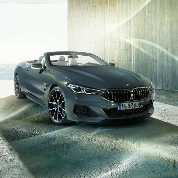 BMW M850i xDrive Cabrio, vue de trois quarts avant G14. BMW M850i xDrive Cabrio en Dravitgrau metallic avec capote ouverte, vue de trois quarts avant, à l’arrêt devant le littoral G14.