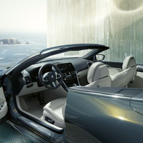 BMW M850i xDrive Cabrio, habitacle G14. BMW M850i xDrive Cabrio in Dravitgrau metallic avec capote ouverte, habitacle avec volant M en cuir et garnissage BMW Individual en cuir Merino Elfenbeinweiss G14.
