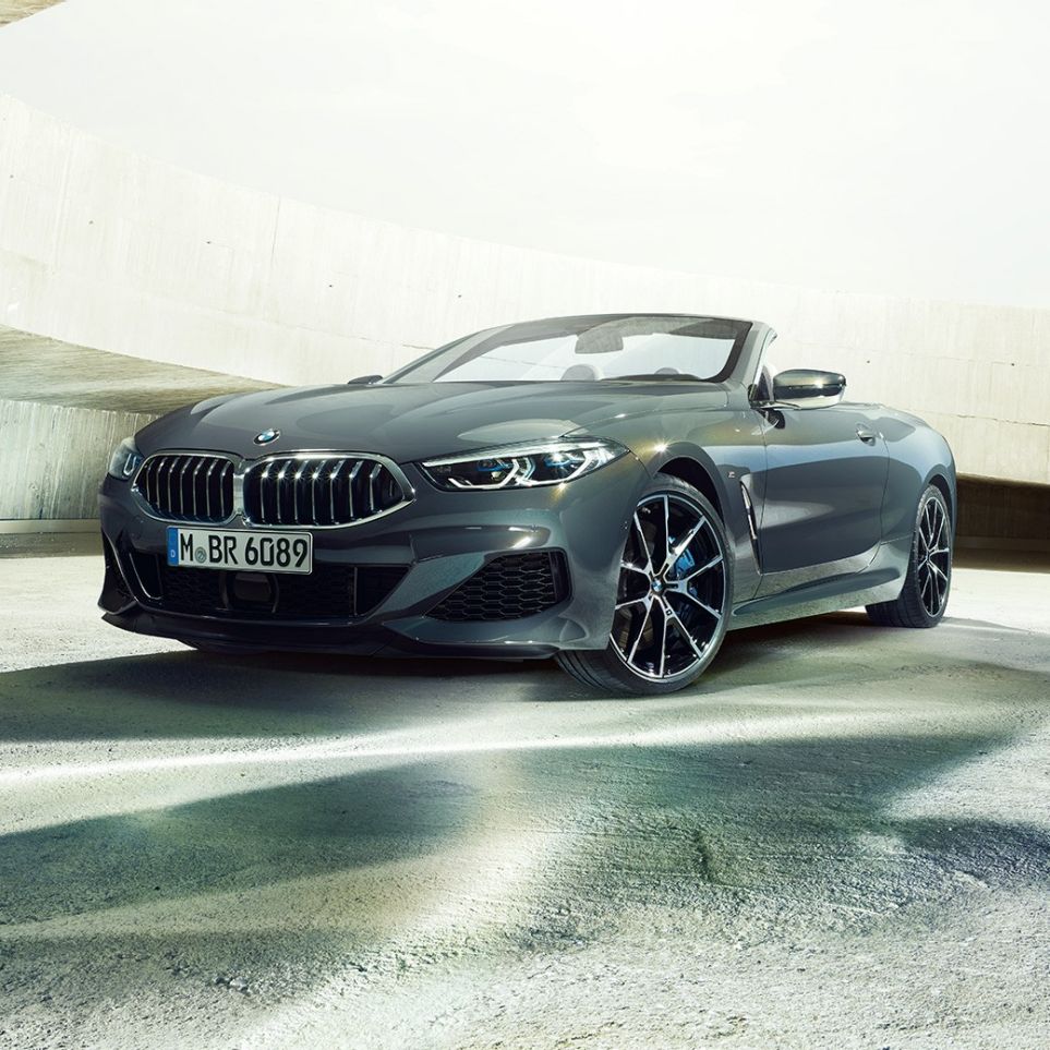 BMW M850i xDrive Cabrio, vue de trois quarts avant G14. BMW M850i xDrive Cabrio en Dravitgrau metallic avec capote ouverte, vue de trois quarts avant, à l’arrêt dans un bâtiment en béton G14.