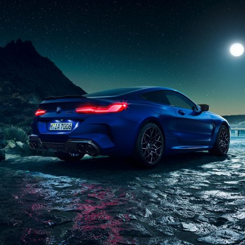 BMW M8 Competition, vue de trois quarts arrière F92. BMW M8 Competition Coupé en Marina Bay Blau metallic avec feux arrière LED allumés, vue de trois quarts arrière à l’arrêt, sous la pleine lune F92.