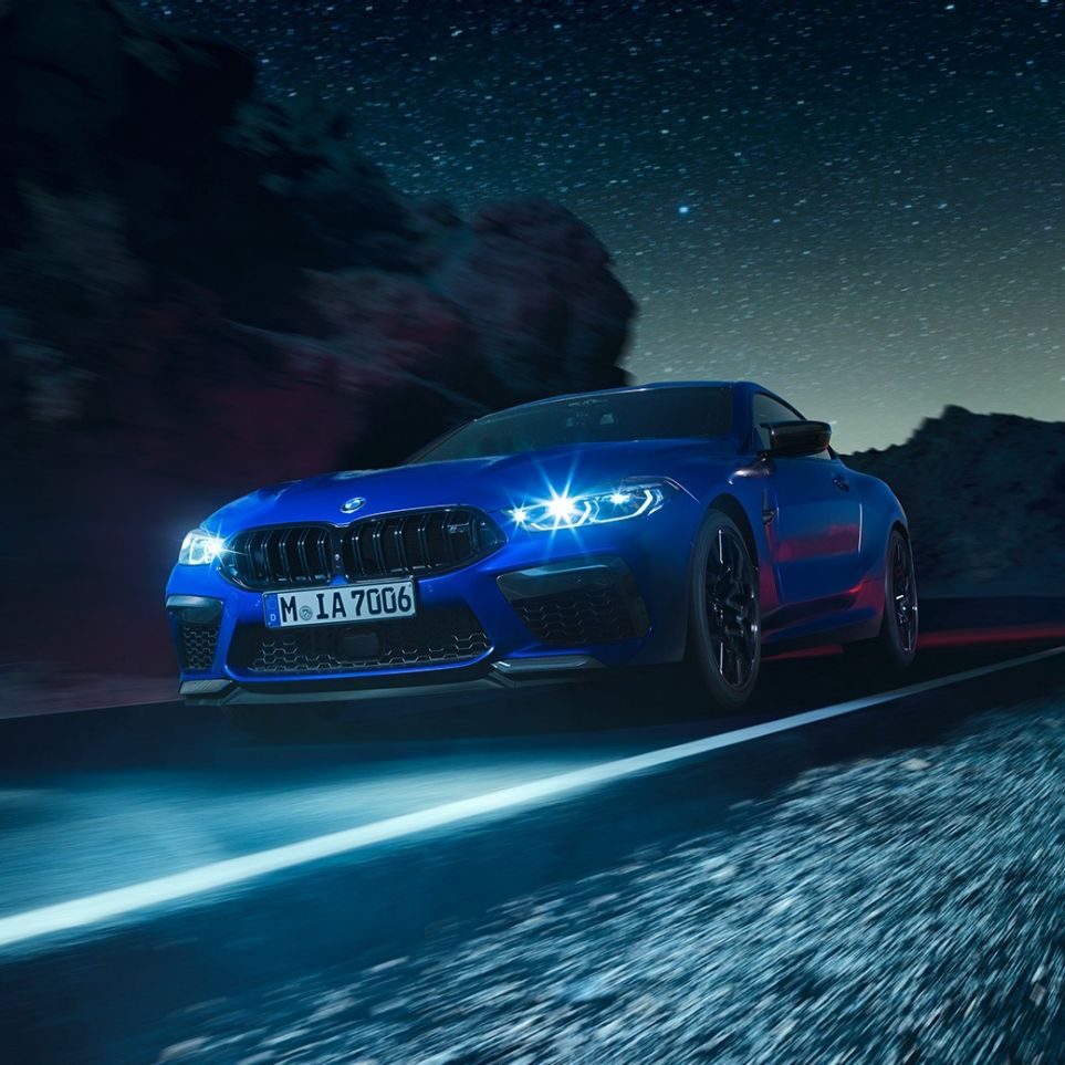 BMW M8 Competition Coupé en marche, vue de trois quarts avant F92. BMW M8 Competition Coupé en Marina Bay Blau metallic avec phares LED allumés, vue de trois quarts avant en marche, de nuit F92.