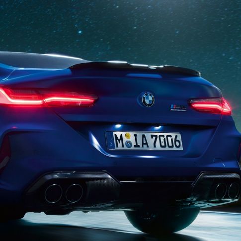 Diffuseur M en Carbon Schwarz F92. BMW M8 Competition Coupé en Marina Bay Blau metallic, vue en gros plan de la poupe de nuit, avec diffuseur M en Carbon Schwarz F92.