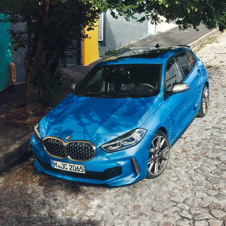 1 Reeks BMW langs de kant van de weg F40. 1 Reeks BMW in Misano Blau metallic, driekwart vooraanzicht bij het parkeren langs de weg vanuit vogelperspectief. F40