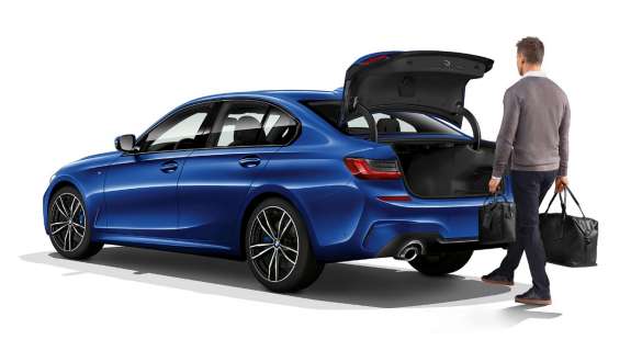BMW 3 Reeks Berline, automatische achterklepbediening G20. Driekwart achteraanzicht van de BMW 3 Reeks Berline in stilstand met bestuurder, die de achterklep automatisch opent met de voet G20.
