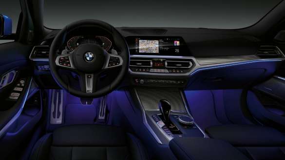 BMW 3 Reeks Berline, sfeerverlichting G20. Vooraanzicht van de cockpit van de BMW 3 Reeks Berline aan bestuurderszijde met voetruimte blauw verlicht door sfeerverlichting G20.
