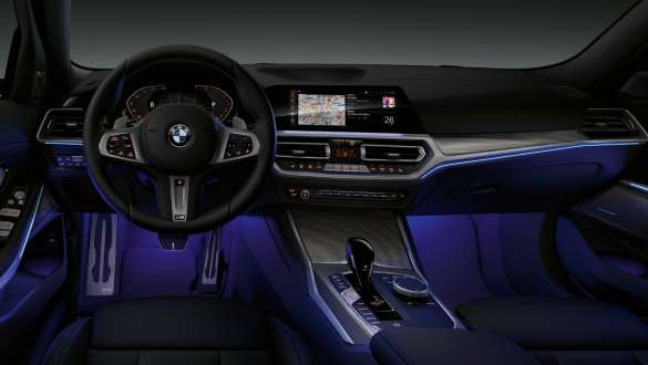 BMW 3 Reeks Berline (G20), sfeerverlichting. Vooraanzicht van de cockpit van de BMW 3 Reeks Berline (G20) aan bestuurderszijde met voetruimte blauw verlicht door sfeerverlichting.