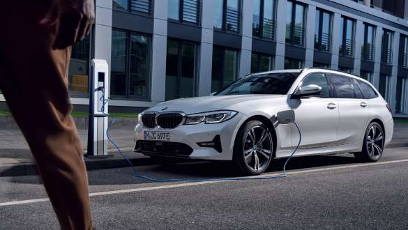Plug-in-hybride BMW 3 Reeks Touring 2021 G21 driekwart vooraanzicht ladend Plug-in-hybride BMW 3 Reeks Touring 2021 G21 driekwart vooraanzicht ladend voor gebouw