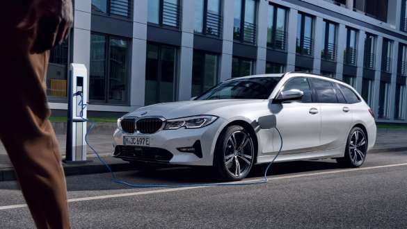 Plug-in-hybride BMW 3 Reeks Touring 2021 G21 driekwart vooraanzicht ladend Plug-in-hybride BMW 3 Reeks Touring 2021 G21 driekwart vooraanzicht ladend voor gebouw