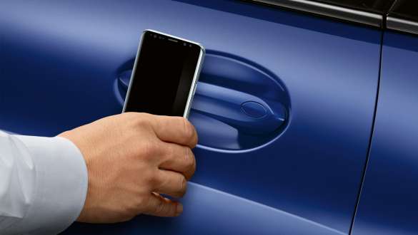 BMW Digital Key BMW 8 Reeks Coupé G15 LCI facelift 2022 BMW Digital Key BMW 8 Reeks Coupé G15 M Portimao Blau metallic LCI facelift 2022 hand houdt smartphone aan autodeur