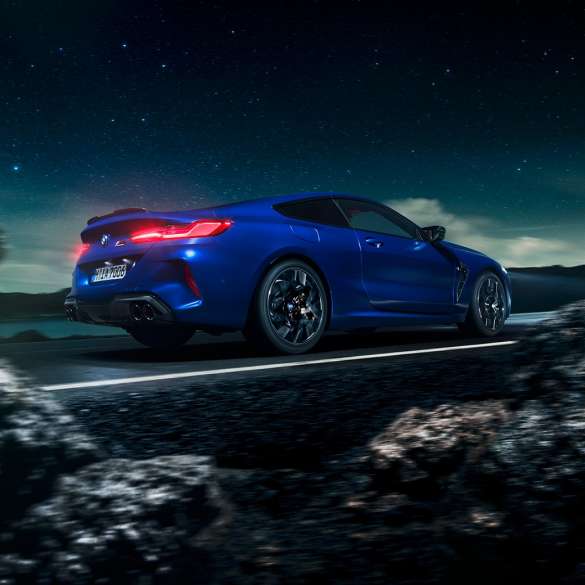 BMW M8 Competition Coupé, driekwart zijaanzicht. BMW M8 Competition Coupé in Marina Bay Blau metallic, driekwart zijaanzicht in beweging met sterrenhemel als achtergrond.