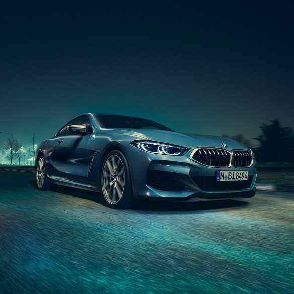 BMW M850i xDrive Coupé, driekwart vooraanzicht links G15. BMW M850i xDrive Coupé in Barcelona Blau metallic, driekwart vooraanzicht links, in beweging ‘s nachts G15.