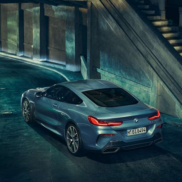 BMW M850i xDrive Coupé, driekwart achteraanzicht links. BMW M850i xDrive Coupé in Barcelona Blau metallic, driekwart achteraanzicht links, stilstaand ‘s nachts.