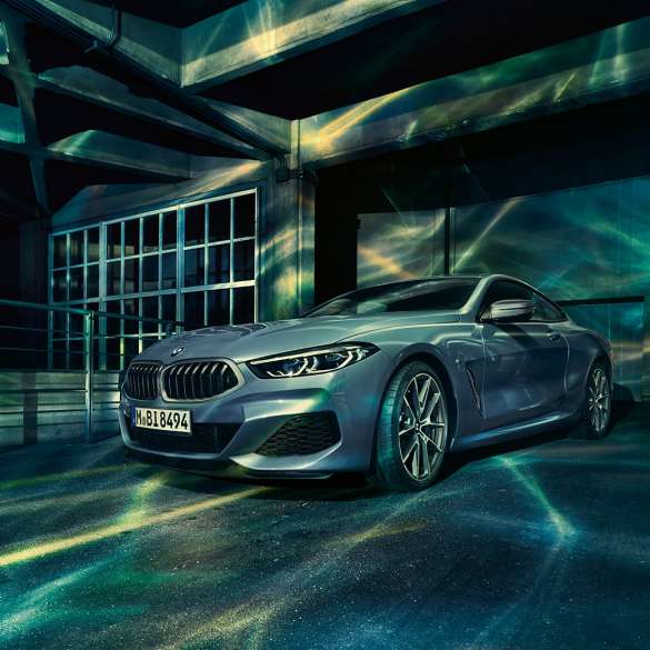 BMW M850i xDrive Coupé, driekwart vooraanzicht G15. BMW M850i xDrive Coupé in Barcelona Blau metallic, driekwart vooraanzicht stilstaand voor gebouw G15.