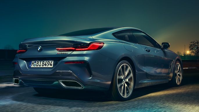 BMW M850i xDrive Coupé, achteraanzicht G15. BMW M850i xDrive Coupé in Barcelona Blau metallic, achteraanzicht, in beweging ‘s nachts G15.