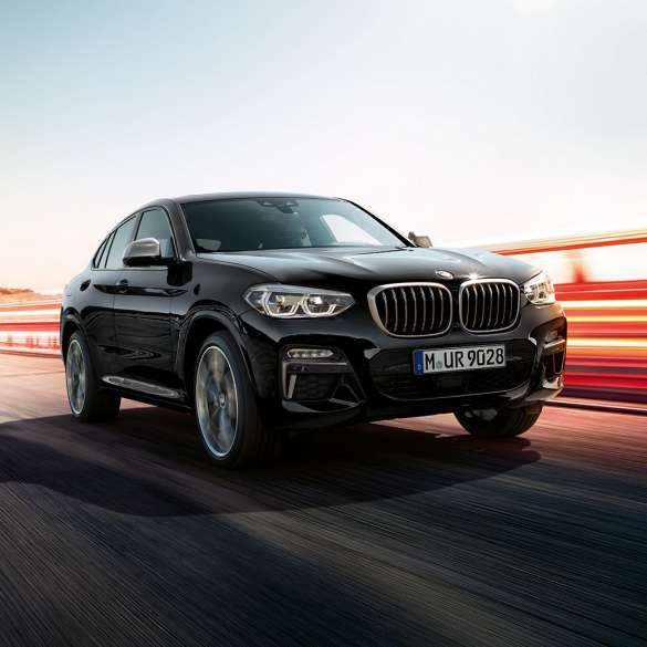 BMW X4 M40i, driekwart achteraanzicht G02. BMW X4 M40i in Saphirschwarz metallic, rijdend, exterieur, driekwart achteraanzicht met lichtstrepen G02.