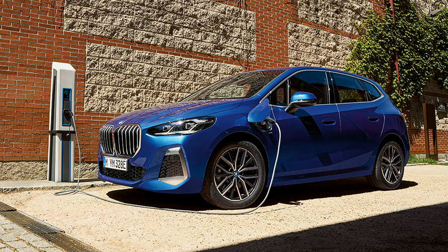 BMW 2 Reeks Active Tourer plug-in-hybride U06 2021 aan de laadpaal BMW 2 Reeks Active Tourer 230e plug-in-hybride U06 2021 M Portimao Blau metallic driekwart zijaanzicht aan de laadpaal