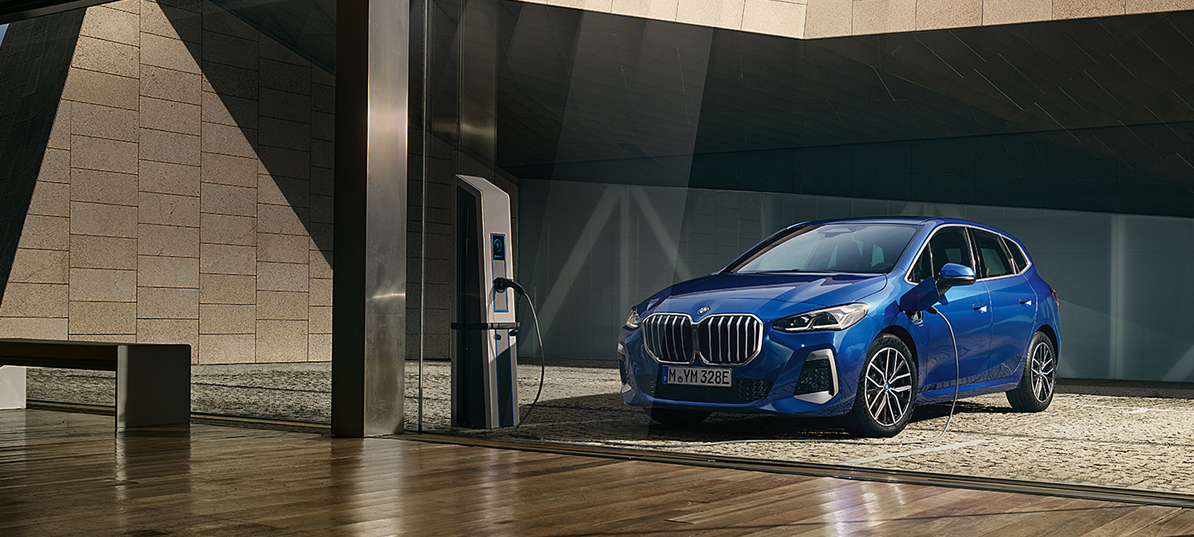 BMW 2 Reeks Active Tourer 230e plug-in-hybride U06 2021 M Portimao Blau metallic driekwart vooraanzicht aan de laadpaal