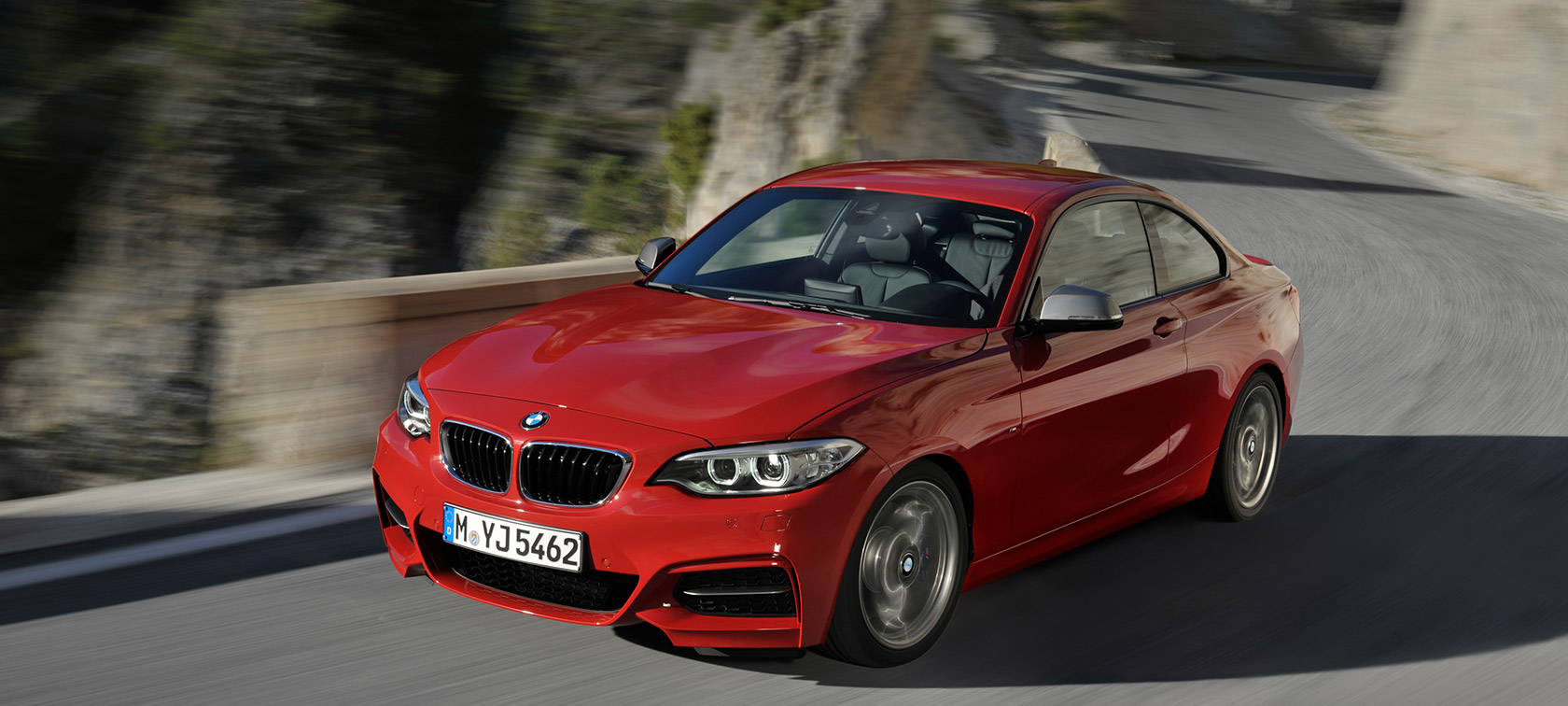 BMW 2 Reeks driekwart vooraanzicht rijdend op de weg door landschap BMW 2 Reeks modellen BMW driekwart vooraanzicht rijdend op de weg door landschap