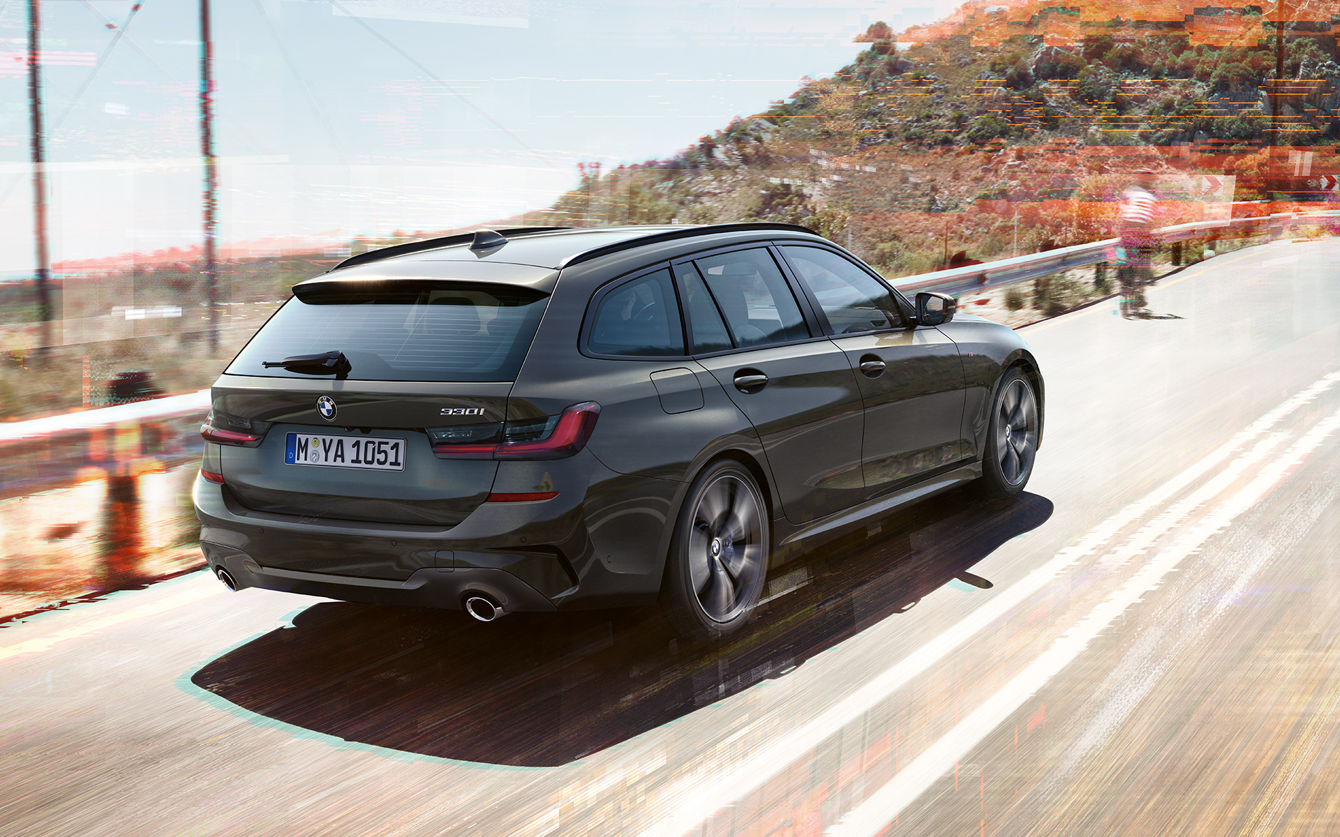BMW Série 3 Touring (G21) Dravitgrau en marche, vue de trois quarts arrière sur un pont devant un environnement rural BMW Série 3 Touring (G21) Dravitgrau en marche, vue de trois quarts arrière sur un pont devant un environnement rural