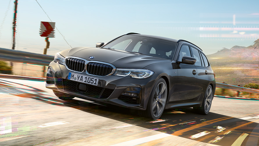 BMW 3 Reeks Touring (G21) Dravitgrau, driekwart vooraanzicht BMW 3 Reeks Touring (G21) Dravitgrau, driekwart vooraanzicht tijdens het rijden in een landelijke omgeving
