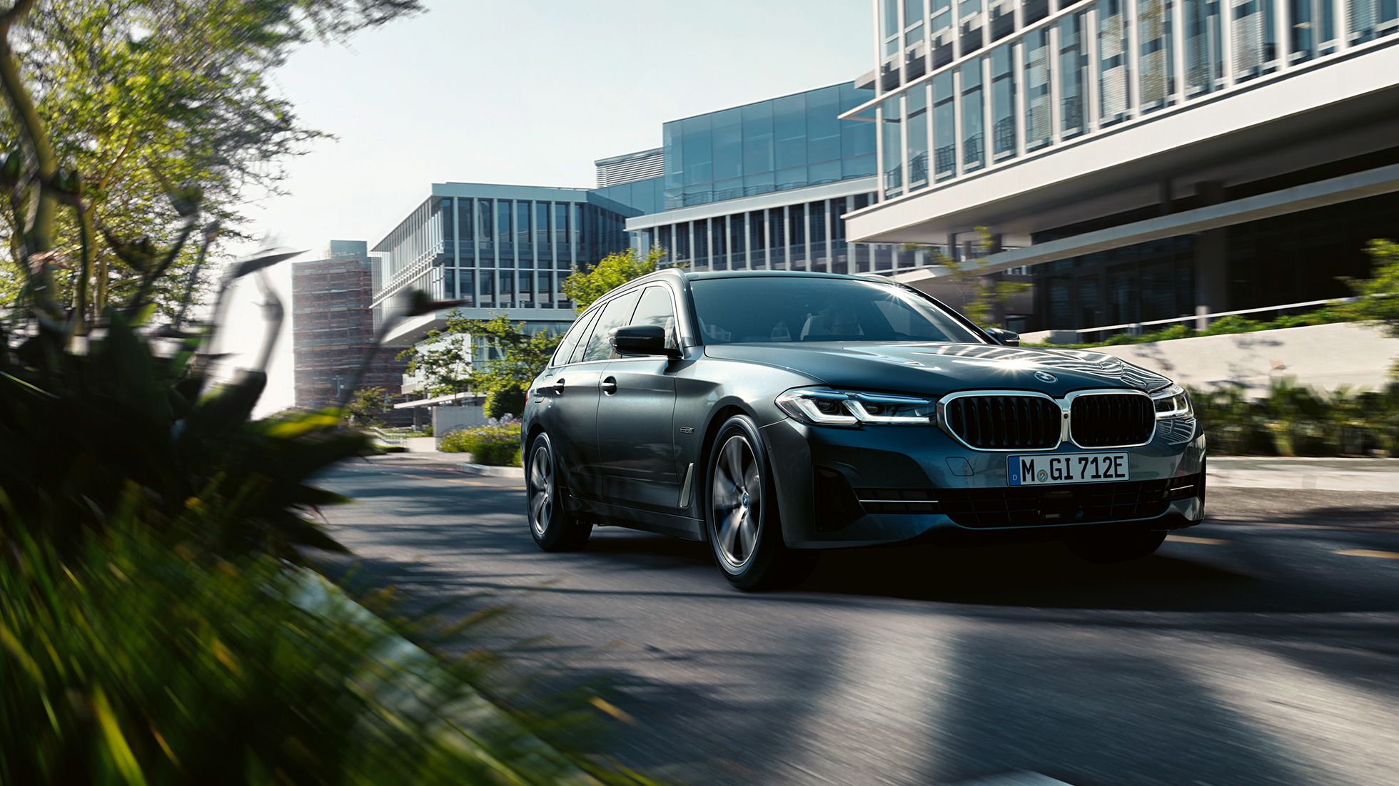 Extérieur de la BMW Série 5 Touring G31 BMW Série 5 Touring G31 restylage 2020 en Phytonicblau, vue de trois quarts avant, en mouvement dans un paysage urbain