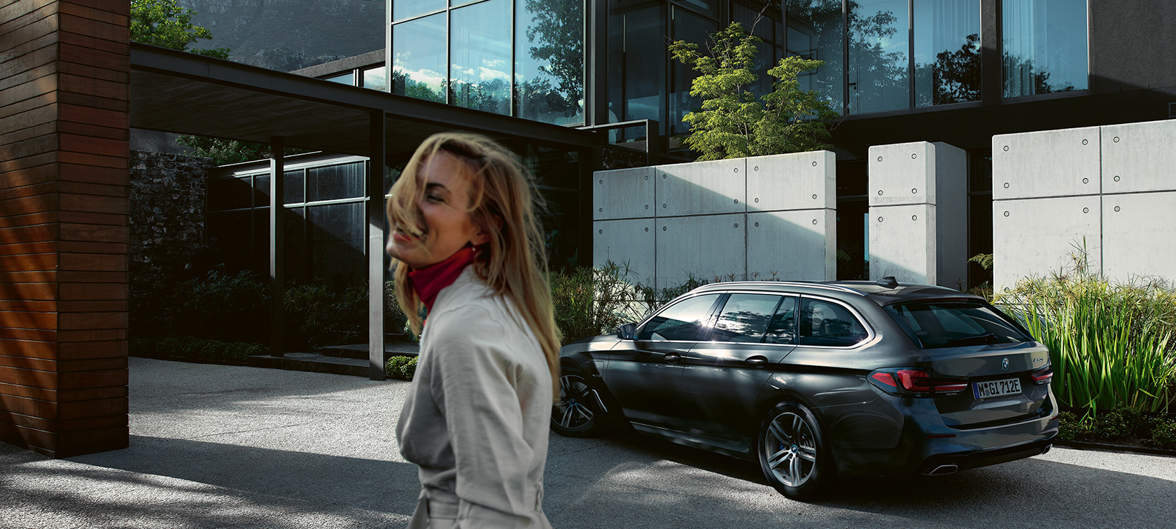 Femme devant une BMW Série 5 Touring G31 garée BMW Série 5 Touring G31 restylage 2020 femme devant la BMW garée