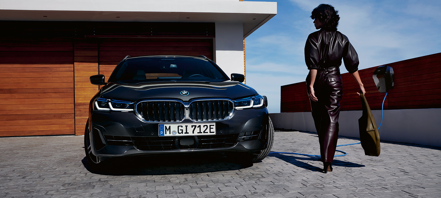 BMW hybride rechargeable Série 5 Touring 2021 G31 LCI branchée à une borne de recharge, vue avant BMW hybride rechargeable Série 5 Touring 2021 G31 LCI branchée à une borne de recharge, vue avant avec mannequin
