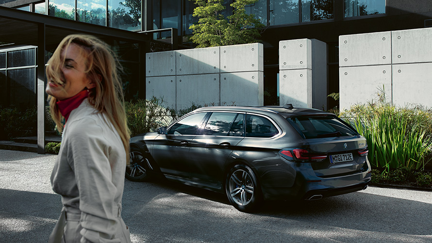 Vue de profil d’une femme devant une BMW Série 5 Touring G31 restylage 2020 en Sophistograu Brilliant Effect metallic 7/8. Vue de profil d’une femme devant une BMW Série 5 Touring G31 restylage 2020 en Sophistograu Brilliant Effect metallic 7/8.
