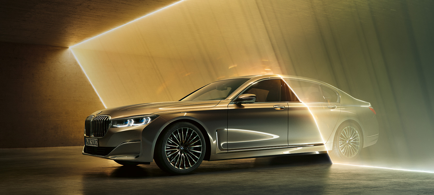 BMW 7 Reeks, luxeberline, in driekwart vooraanzicht G11 BMW 7 Reeks, luxeberline: grijze BMW in driekwart vooraanzicht omgeven door lichtstralen G11