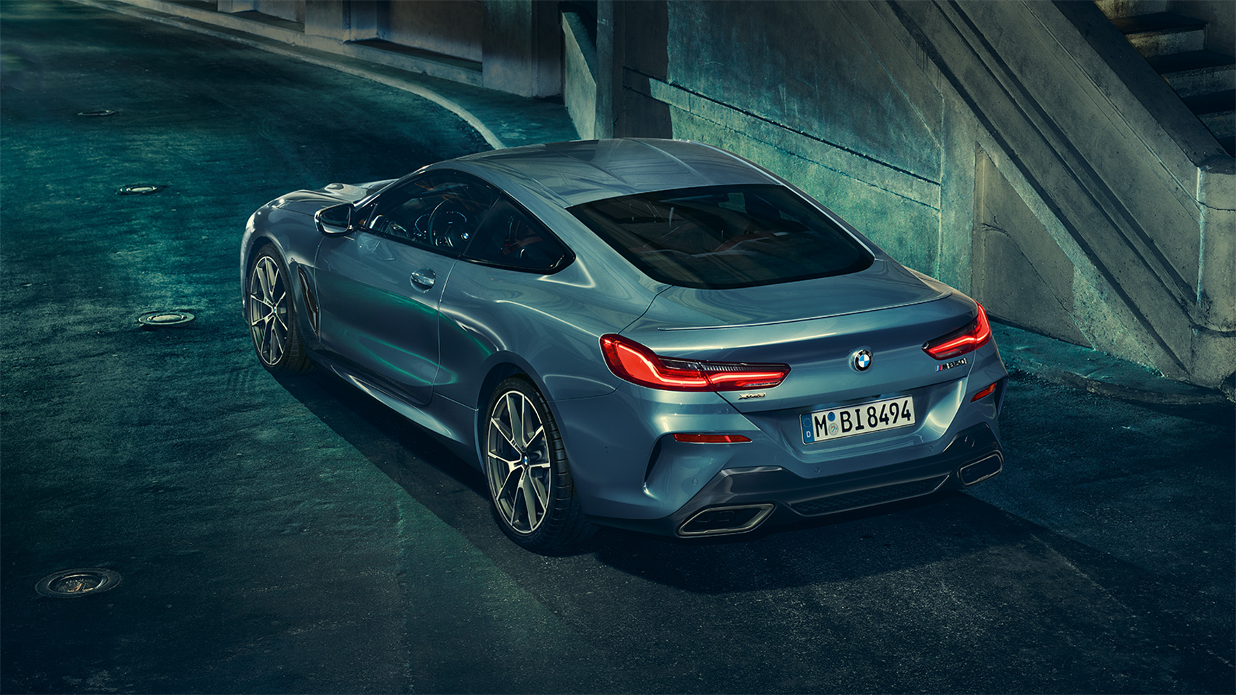BMW 8er Coupé, driekwart achteraanzicht Driekwart achteraanzicht van de BMW 8 Reeks Coupé ’s nachts met de stad als decor.