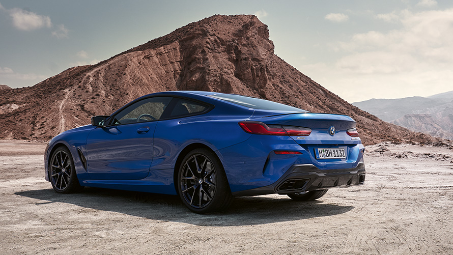 Driekwart achteraanzicht BMW 8 Reeks Coupé M Sportpakket G15 LCI facelift 2022 BMW 8 Reeks Coupé M Sportpakket G15 LCI facelift 2022 M Portimao Blau metallic driekwart achteraanzicht stilstaand voor rotsen