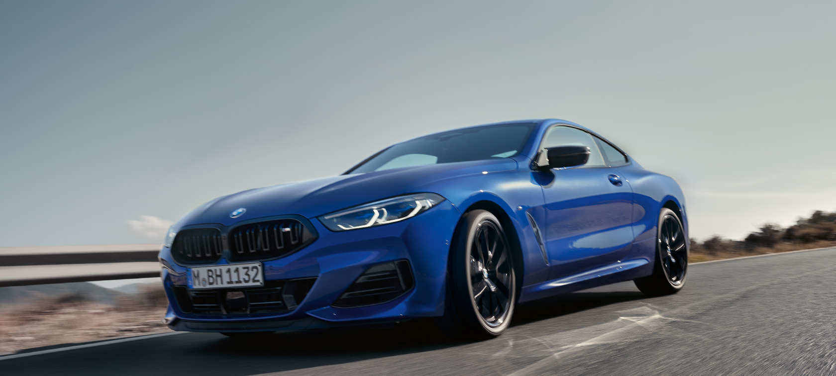 BMW 8 Reeks Coupé G15 LCI facelift 2022 BMW M850i xDrive M Portimao Blau metallic vooraanzicht in kikvorsperspectief rijdend BMW 8 Reeks Coupé G15 LCI facelift 2022 BMW M850i xDrive M Portimao Blau metallic vooraanzicht in kikvorsperspectief rijdend op landweg door een heuvelachtig landschap