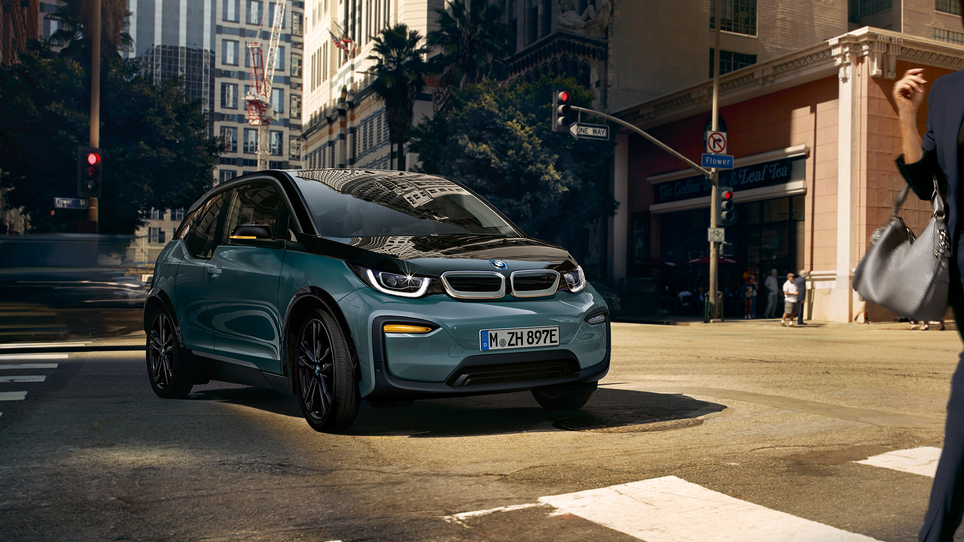 BMW i3 2018, vue de trois quarts avant en mouvement I01 BMW i3 I01 2018 Jucarobeige avec accent Frozen Grey metallic vue de trois quarts avant roulant dans un décor urbain
