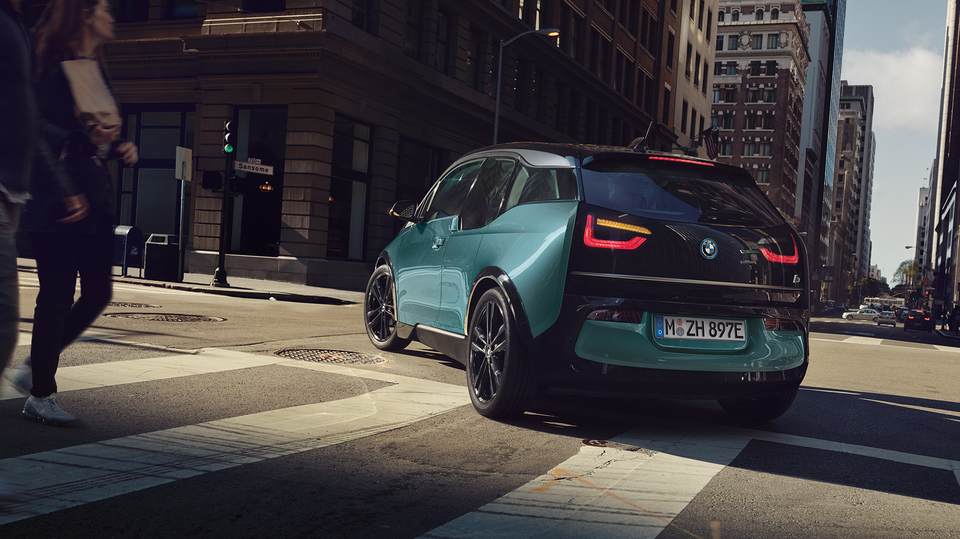 BMW i3 2018 vue de trois quarts arrière, en mouvement I01 BMW i3 I01 2018 Jucarobeige avec accent Frozen Grey metallic vue de trois quarts arrière roulant dans un décor urbain