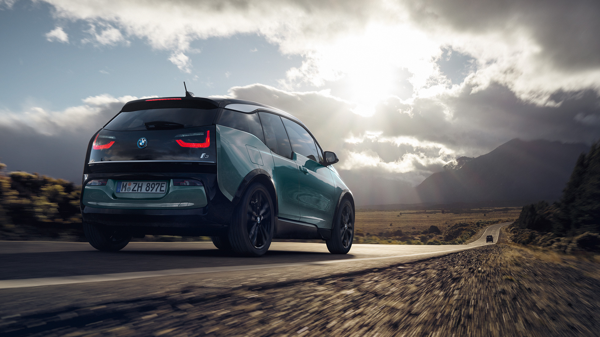 BMW i3 2018 vue de trois quarts arrière roulant sur une route de campagne I01 BMW i3 I01 2018 Jucarobeige avec accent Frozen Grey metallic vue de trois quarts arrière roulant sur une route de campagne