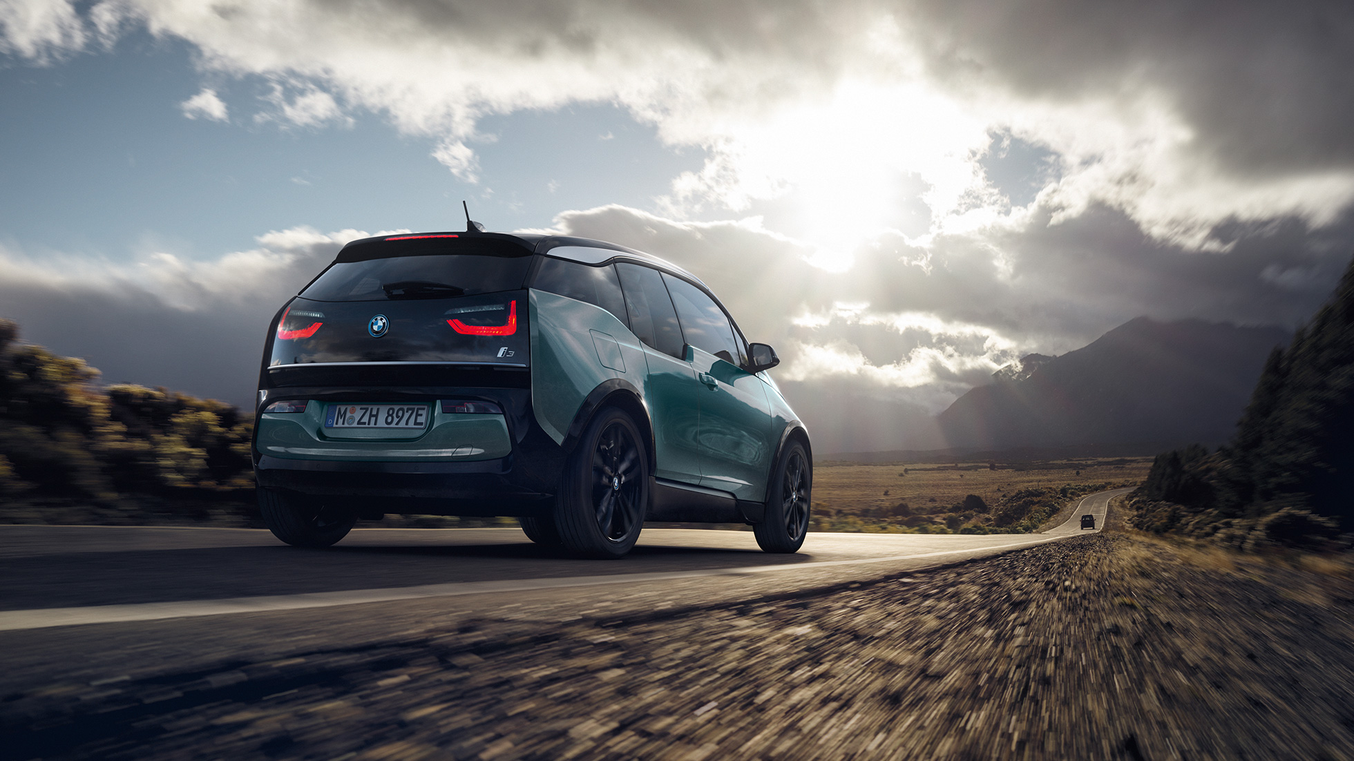 BMW i3 2018 Jucarobeige vue de trois quarts arrière roulant sur une route de campagne I01 BMW i3 I01 2018 Jucarobeige avec accent Frozen Grey metallic vue de trois quarts arrière roulant sur une route de campagne