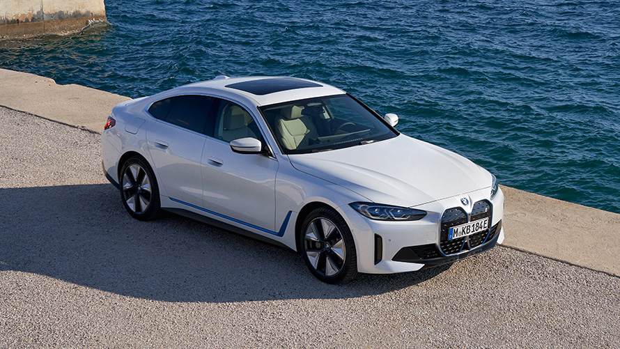 Driekwart vooraanzicht BMW i4 eDrive40 G26 2021 op de kade BMW i4 eDrive40 G26 2021 Mineralweiß driekwart vooraanzicht op de kade