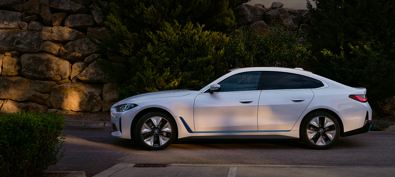 BMW i4 eDrive40 G26 2021 Mineralweiß driekwart vooraanzicht stilstaand aan meer met heuvels op de achtergrond