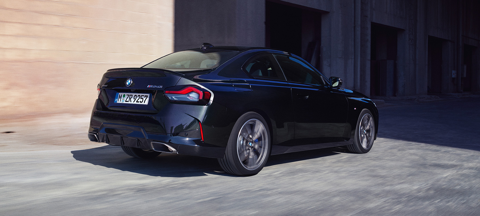 Driekwart achteraanzicht BMW M240i xDrive Coupé G42 2021 BMW M240i xDrive Coupé G42 2021 Saphirschwarz metallic driekwart achteraanzicht rijdend