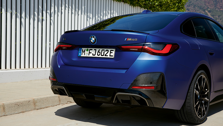 BMW i4 M50 G26 2021 vue de trois quarts arrière BMW i4 M50 G26 2021 BMW Individual Frozen Portimao Blau metallic vue de trois quarts arrière à l’arrêt près d’une clotûre blanche