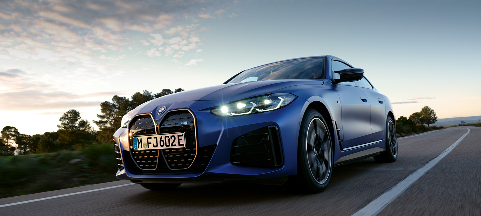 BMW i4 M50 G26 2021 Vue de profil devant un terrain pierreux BMW i4 M50 G26 2021 BMW Individual Frozen Portimao Blau metallic vue de profil à l’arrêt devant un terrain pierreux