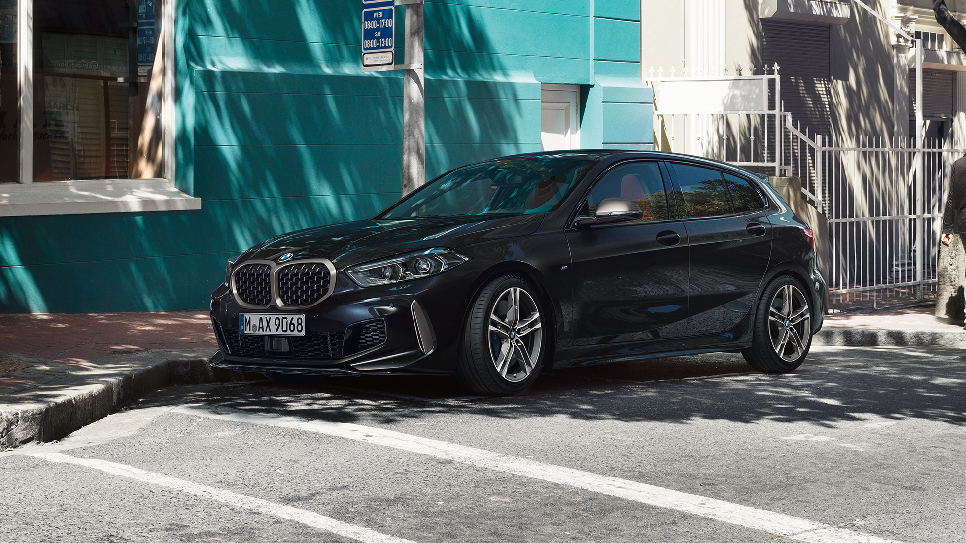 BMW M135i xDrive, vue de trois quarts de profil F40. BMW M135i xDrive en Saphirschwarz metallic, vue de trois quarts de profil, en stationnement F40.