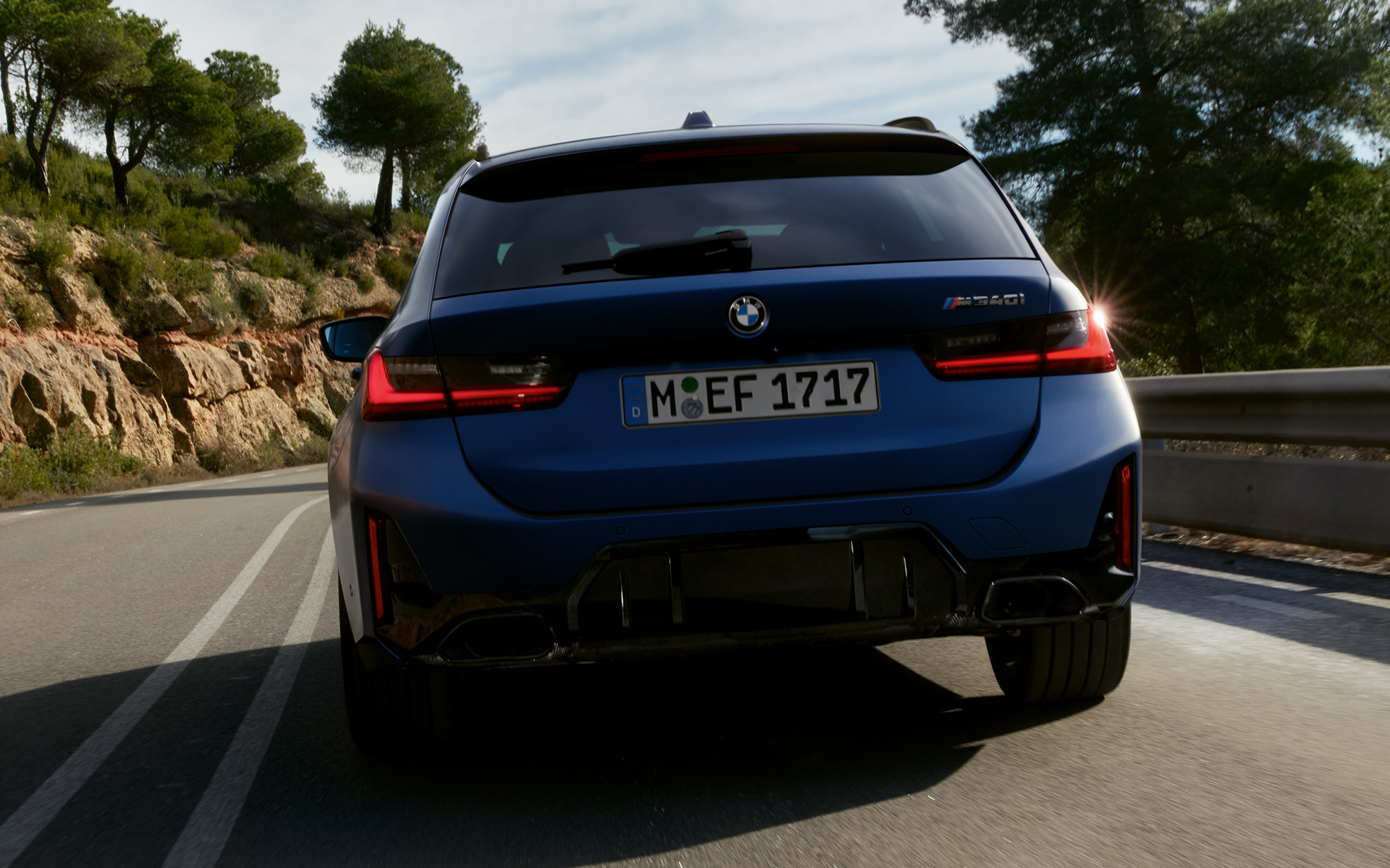 BMW M340i xDrive Touring G21 Frozen Tanzanite Blue vue arrière en mouvement sur la route