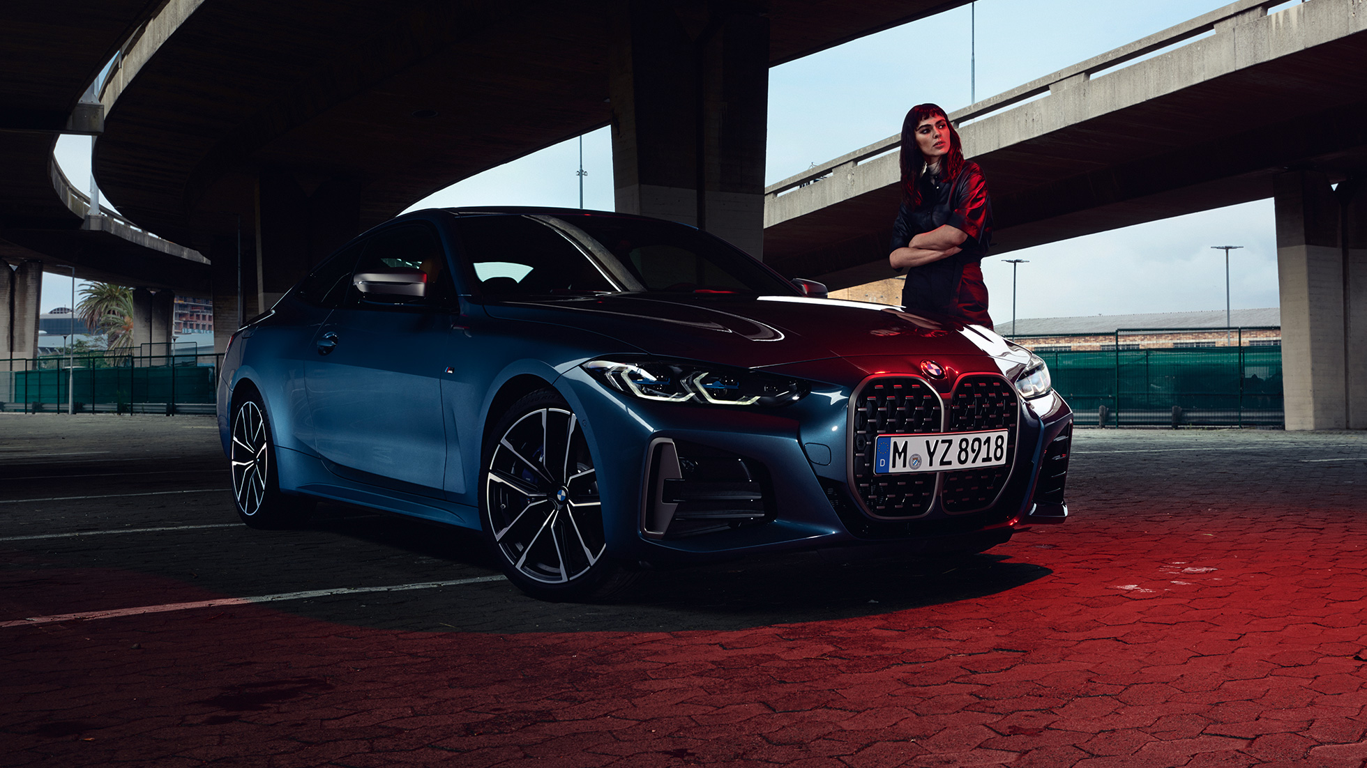 Model staat naast BMW M440i xDrive Coupé G22 2020 driekwart zijaanzicht BMW M440i xDrive Coupé Arctic Race Blue metallic G22 2020 driekwart zijaanzicht met model