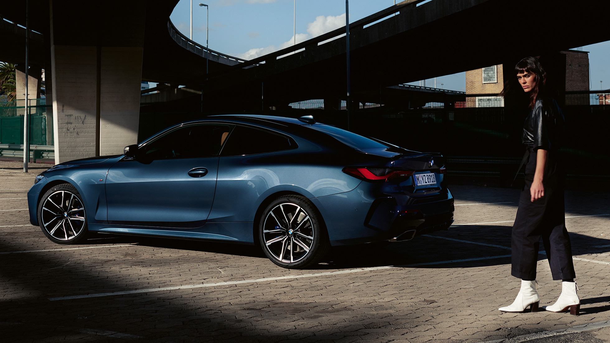 Driekwart achteraanzicht met model BMW M440i xDrive Coupé G22 2020 BMW M440i xDrive Coupé Arctic Race Blue metallic G22 2020 driekwart achteraanzicht met model